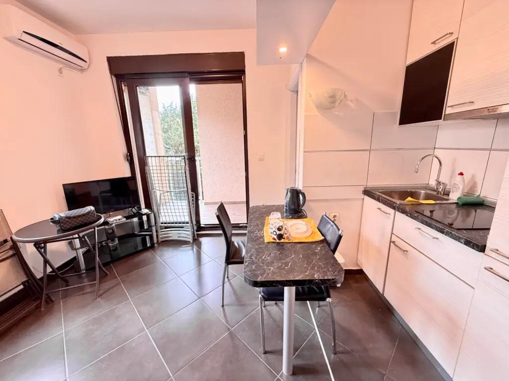 Small kitchen and dining area with balcony door and TV