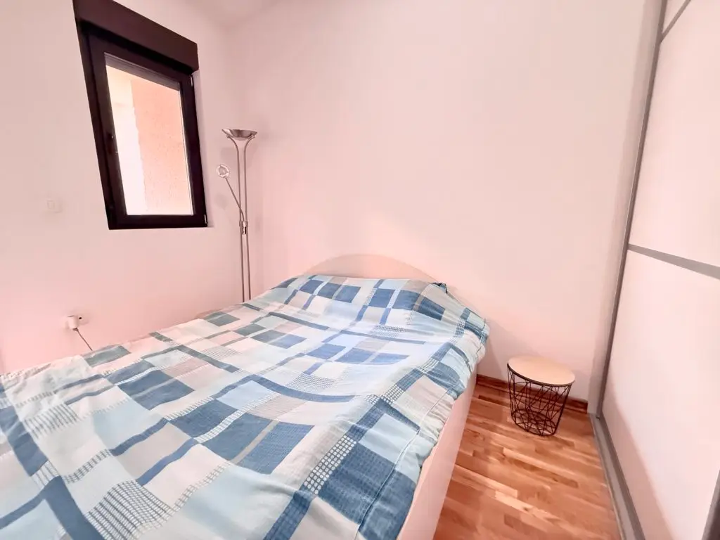 Small bedroom with single bed, blue plaid bedding, and lamp
