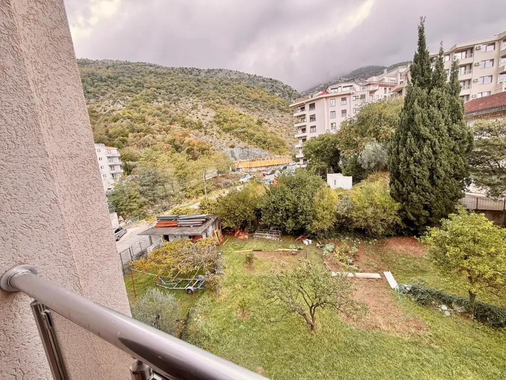 Balcony view of mountains, apartments, and a garden