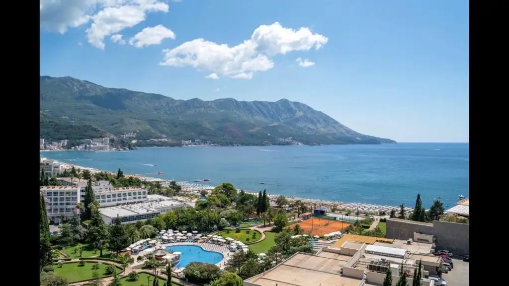 Coastal resort view with pool, sea, and mountains
