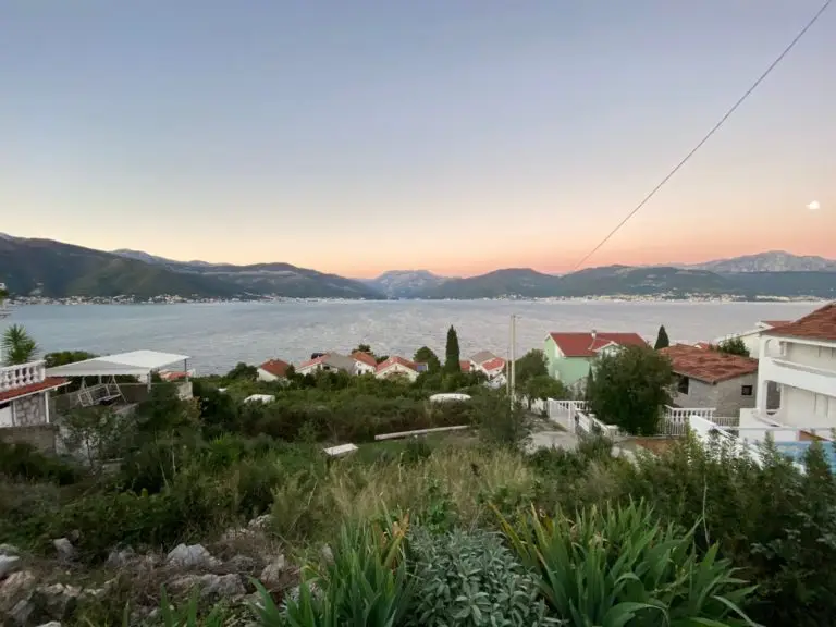 Elevated coastal view with houses, bay, and sunset sky