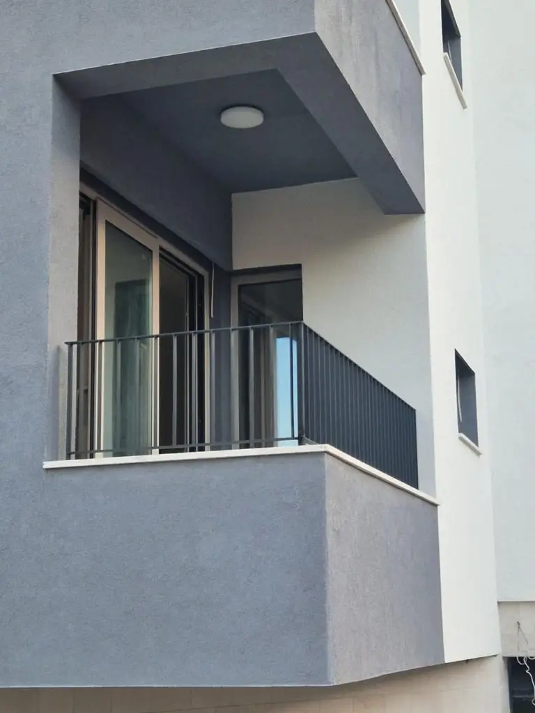 Modern gray apartment balcony with black railing and sliding doors
