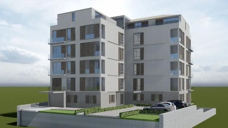 Modern gray apartment building with parked cars and hedges