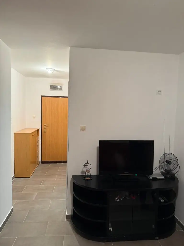 Hallway with black TV stand, small TV, and fan