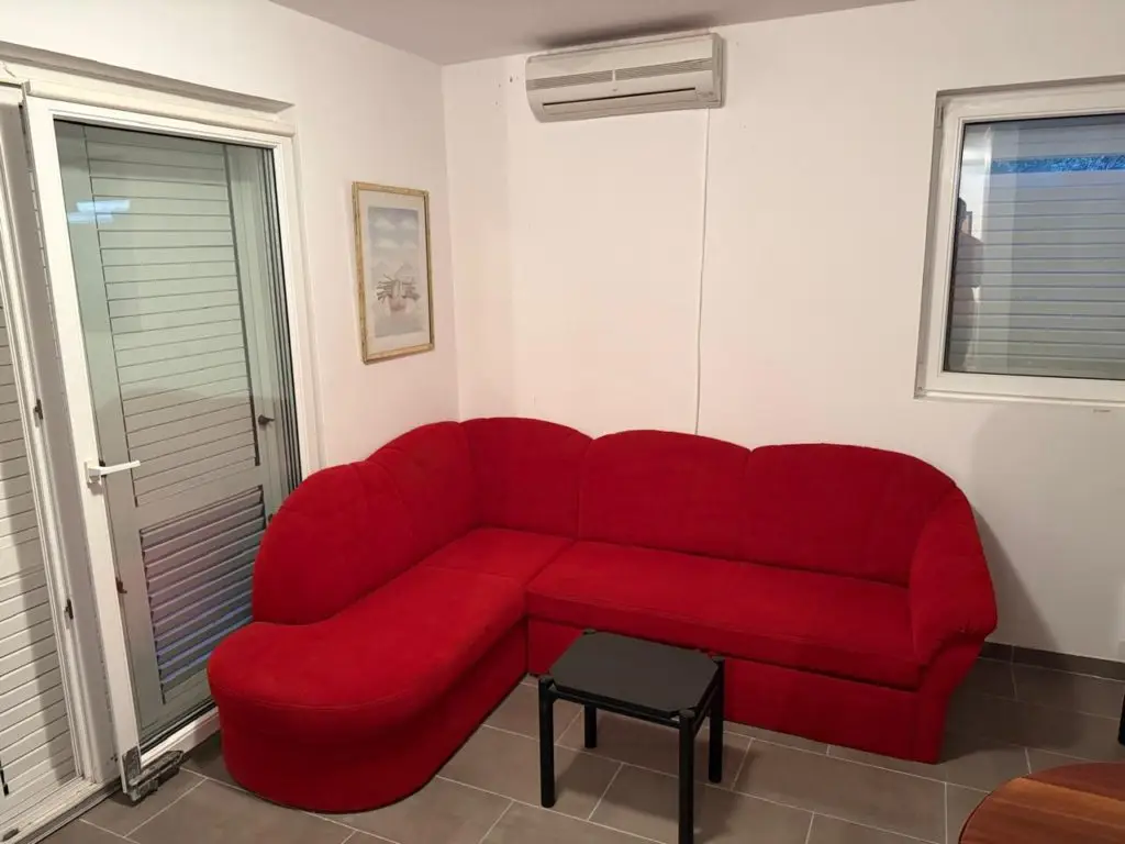 Red sectional sofa with small black table and wall AC