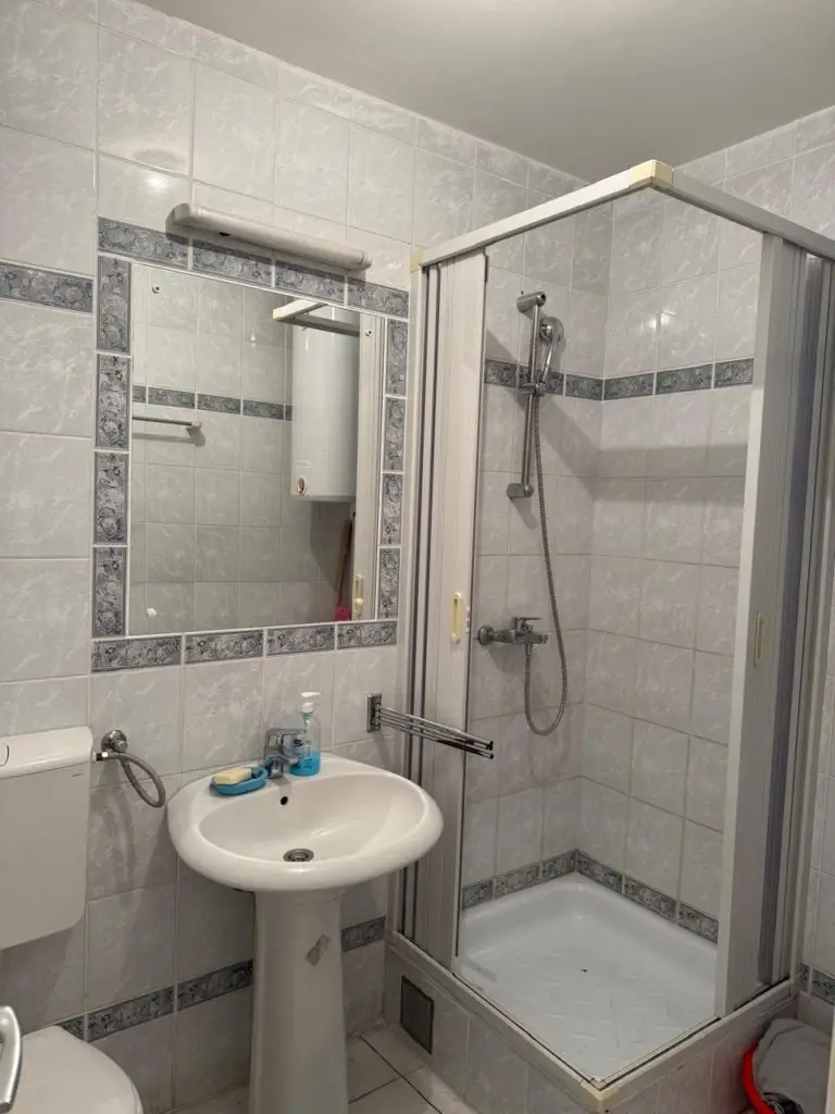 Small bathroom with shower stall, sink, mirror, and toilet