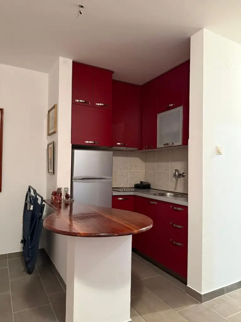 Compact kitchen nook with red cabinets and silver fridge