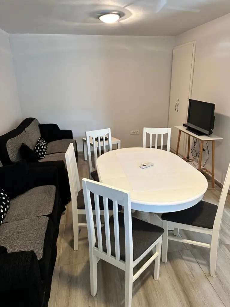 Small living room with sofa, dining table, chairs, and TV