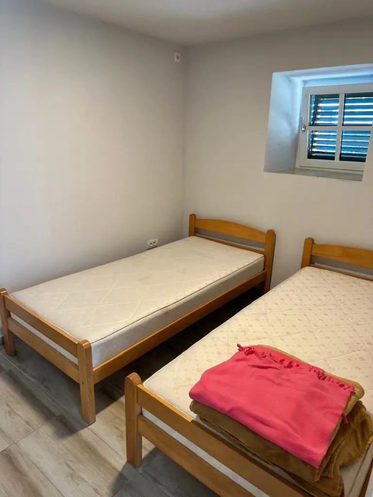 Small bedroom with two single wooden beds and a window