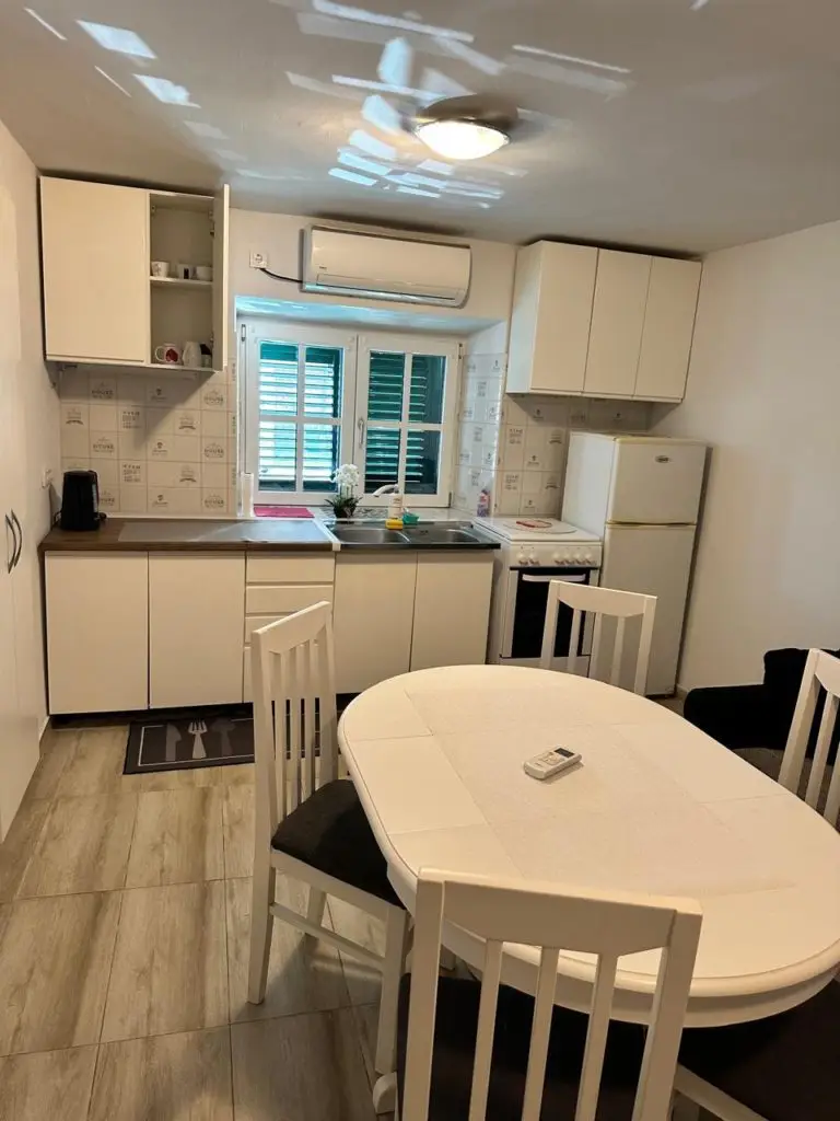 Compact white kitchen with dining table, chairs, and refrigerator