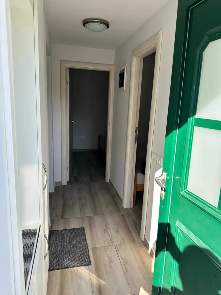 Narrow hallway with open green door and wood floor