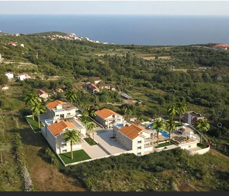Aerial view of four villas with palm trees and sea