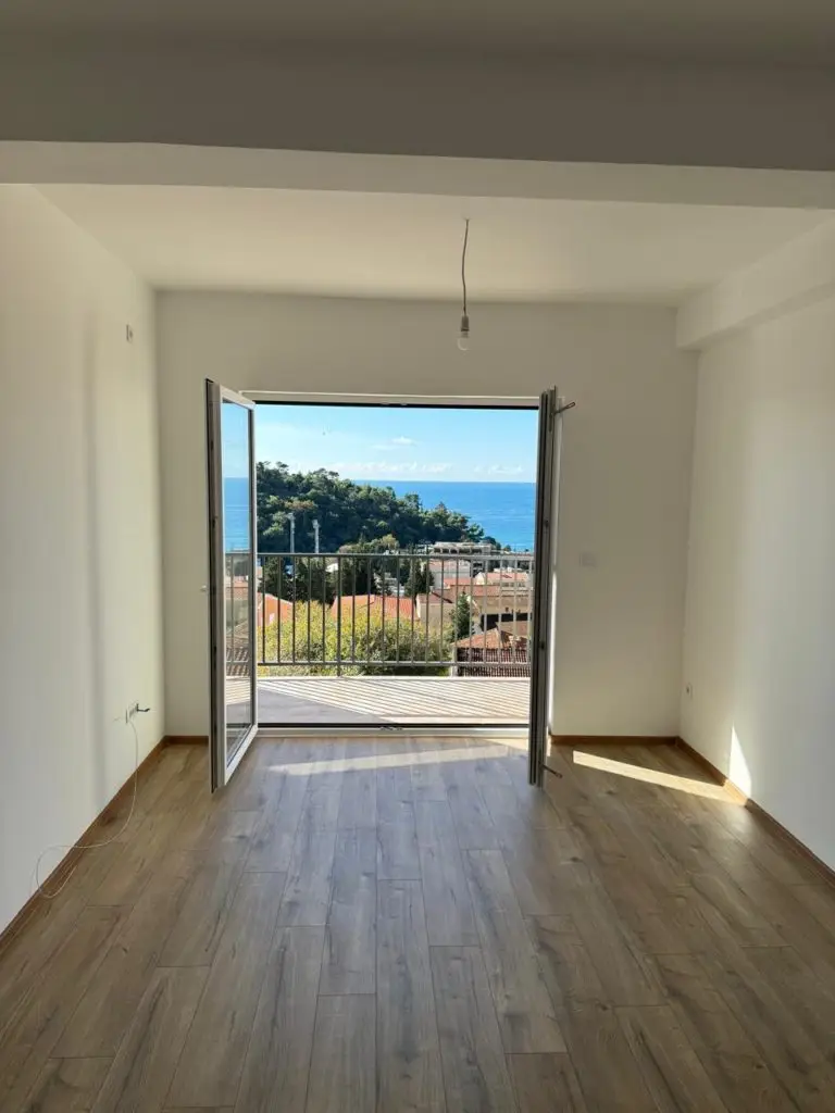 Empty room with wood floor and open balcony doors to sea view