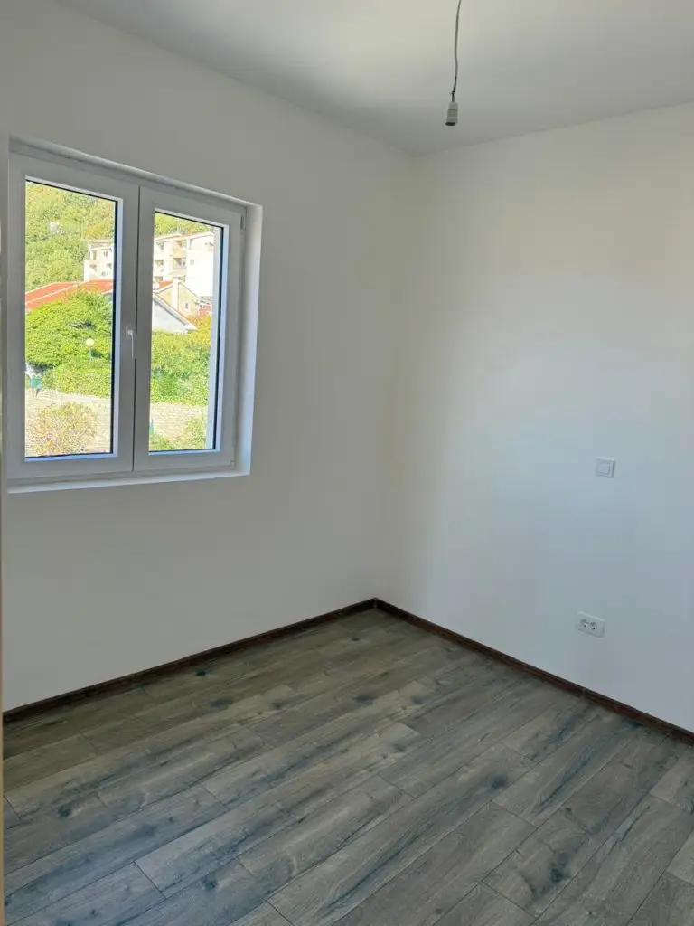 Empty room with window and wood-look flooring