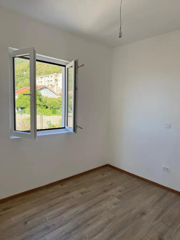 Empty white room with open window and wood floor