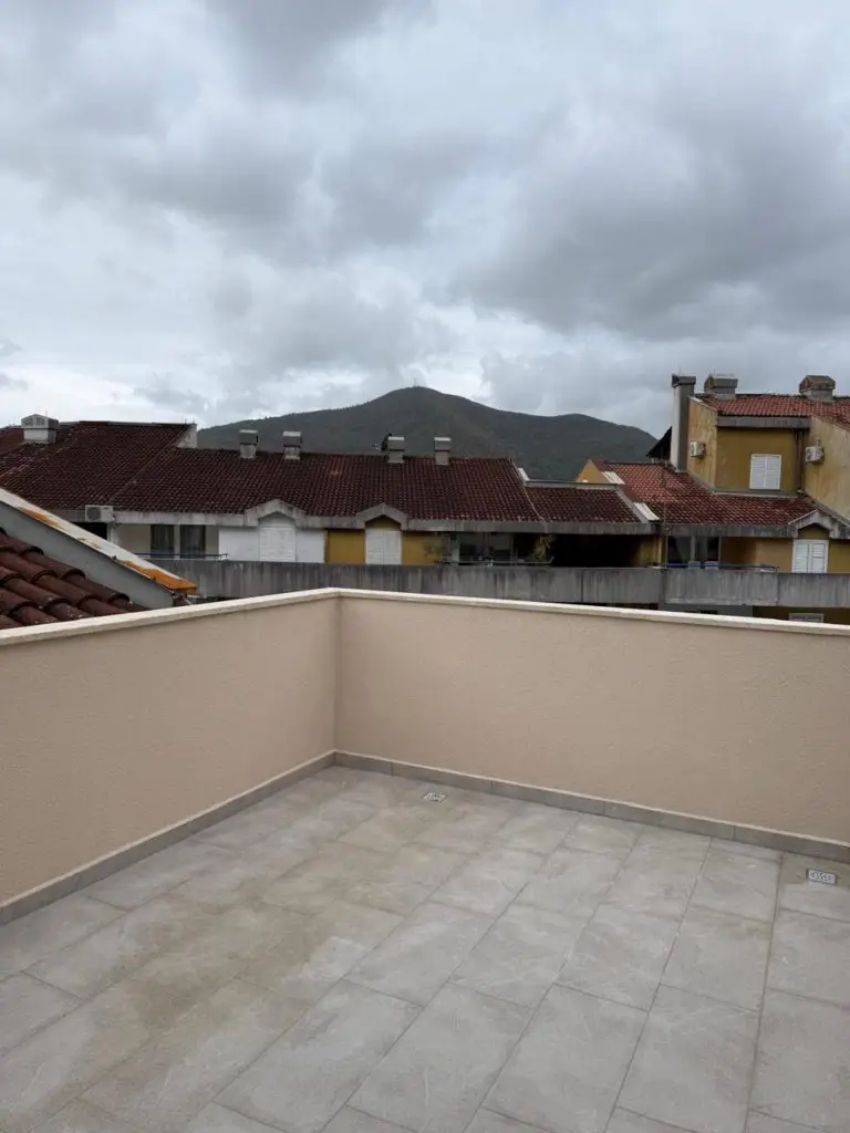 Beige-tiled terrace overlooking rooftops and a cloudy mountain