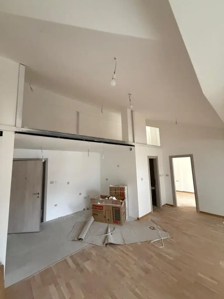 Unfinished apartment interior with loft, wood floor, and cardboard boxes