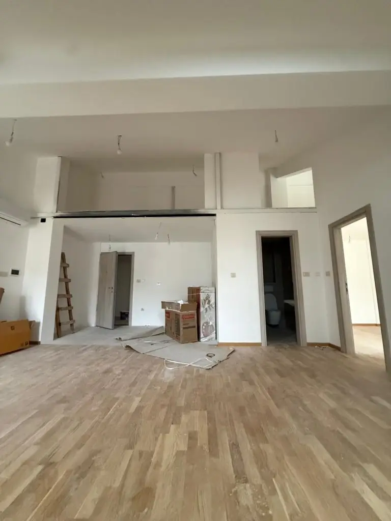 Unfinished apartment interior with loft, wood floor, and open doorways