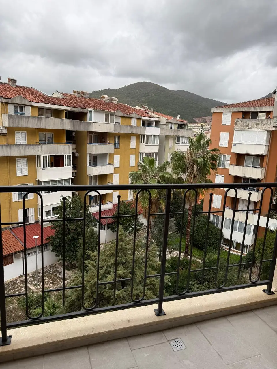 Balcony view of apartment buildings, palm trees, and mountain