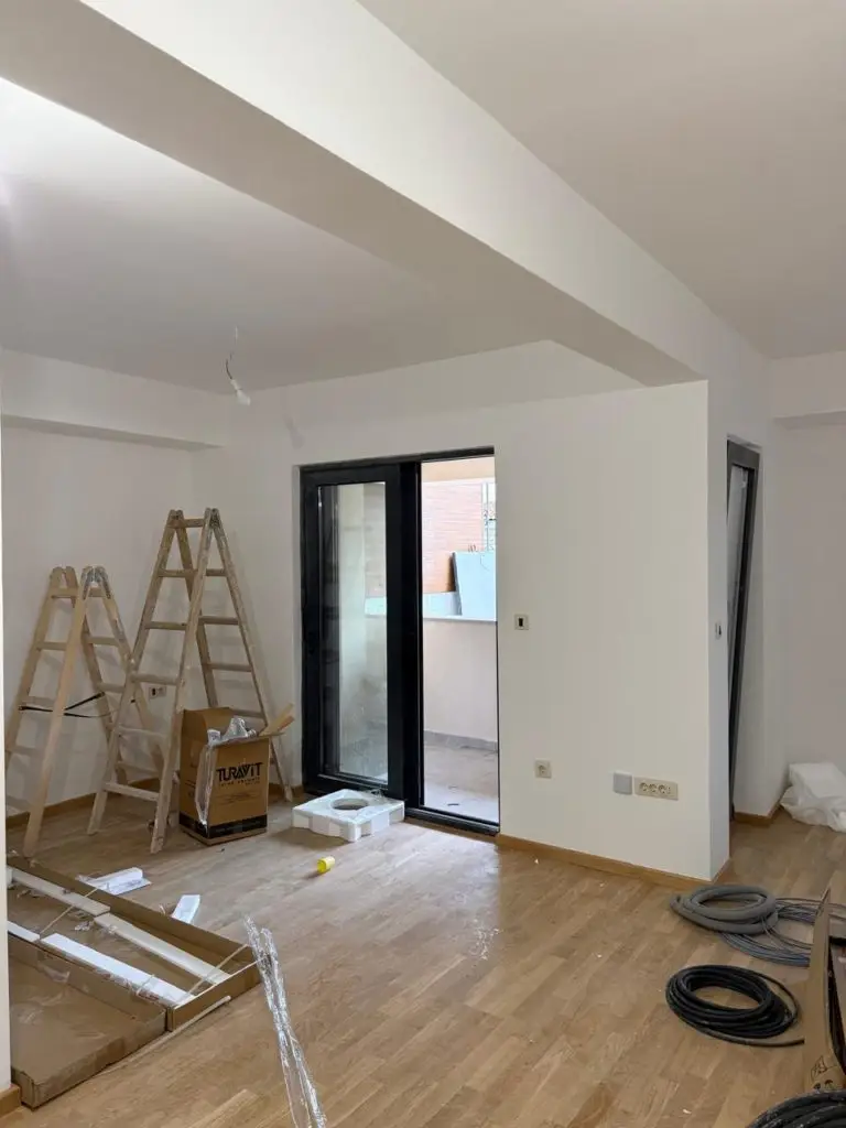 Unfinished white room with ladders, sliding glass door, and cables