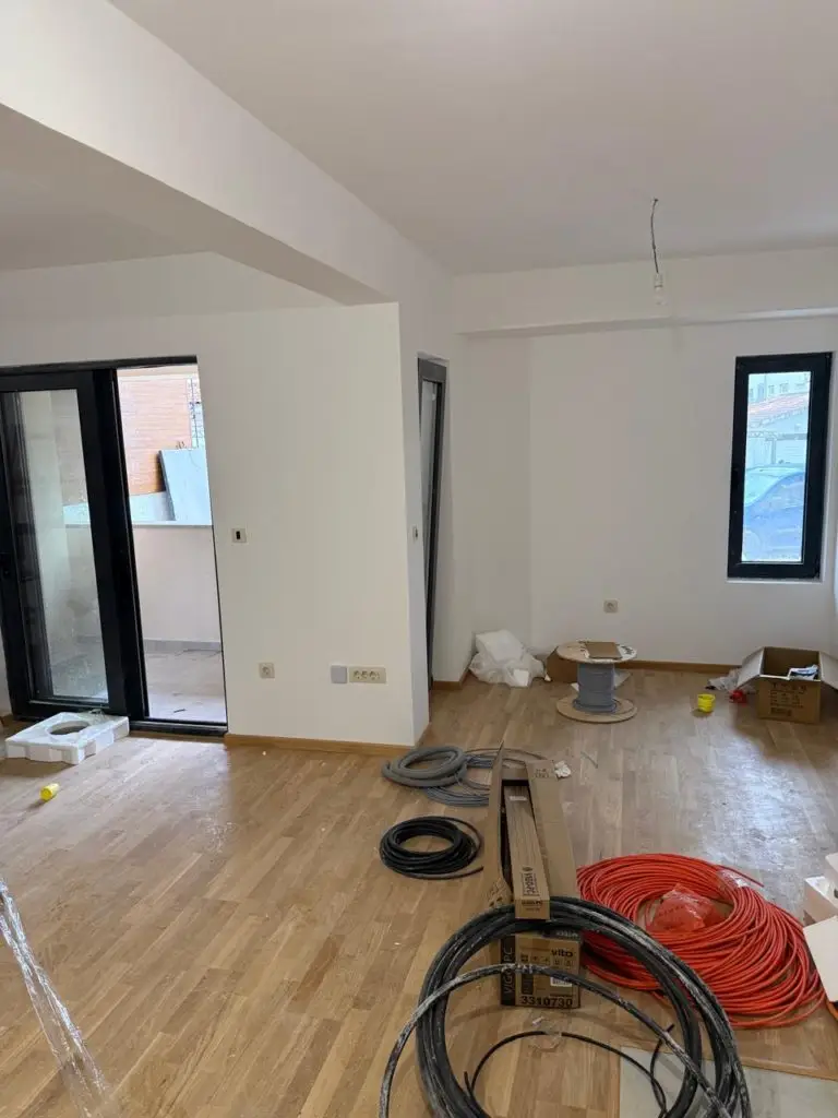 Empty white apartment room with wood floor and cables on floor
