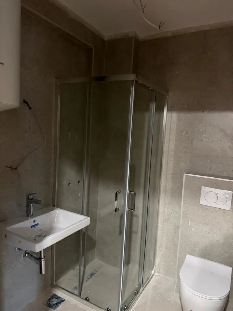 Small bathroom with glass shower, sink, and wall-hung toilet