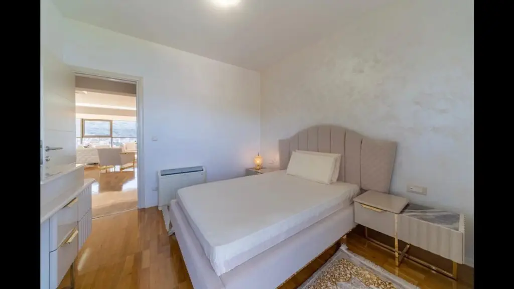 Minimalist bedroom with bed, nightstand, and doorway to bright room
