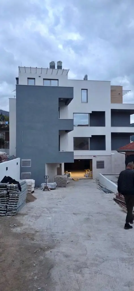 Modern apartment building under construction with a man walking