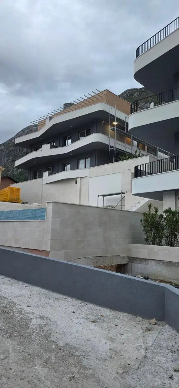 Modern apartment building with curved balconies and mountain backdrop