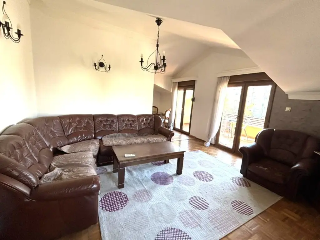 Living room with brown leather sectional, armchair, coffee table, and rug
