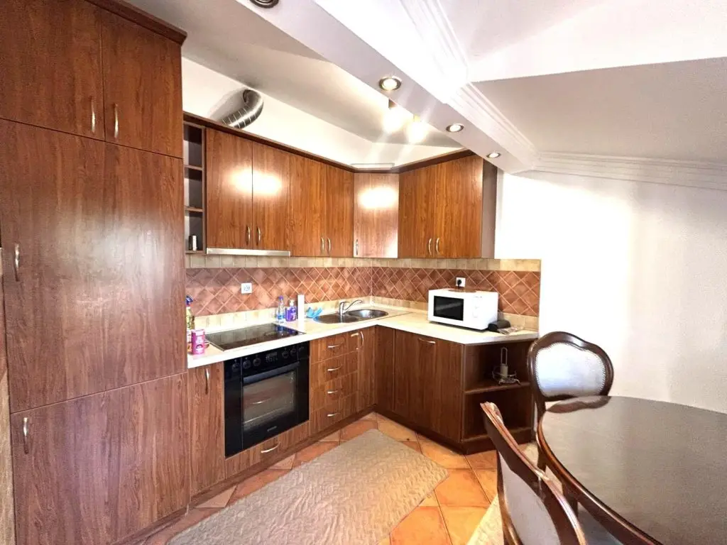Wooden kitchen cabinets with oven, microwave, and dining table
