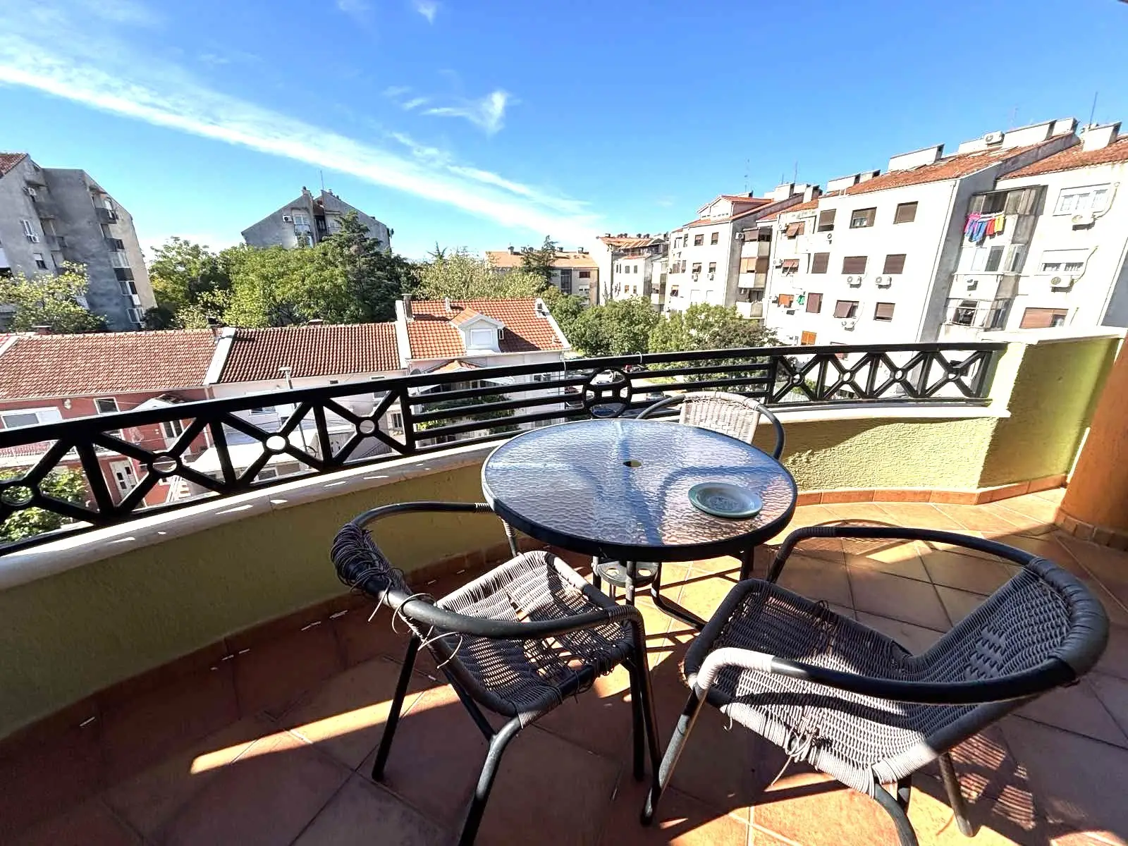 Balcony with round table and three chairs overlooking apartments