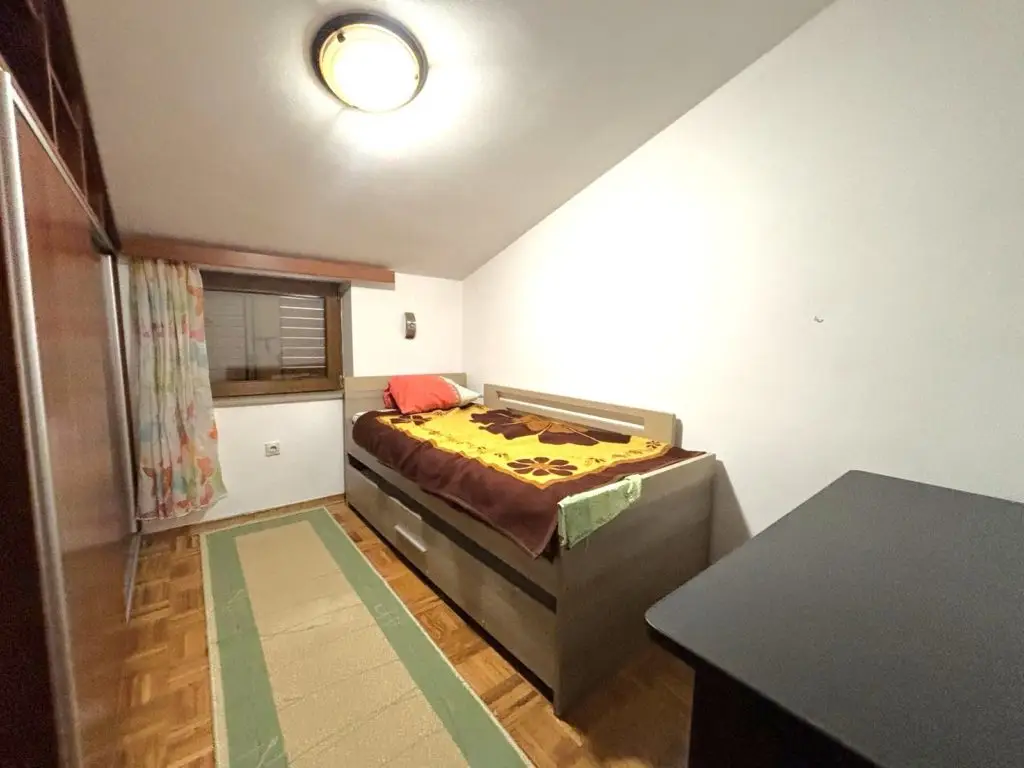 Small bedroom with single bed, wardrobe, and window