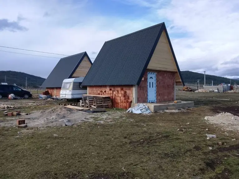 Two A-frame cabins under construction on a bare lot