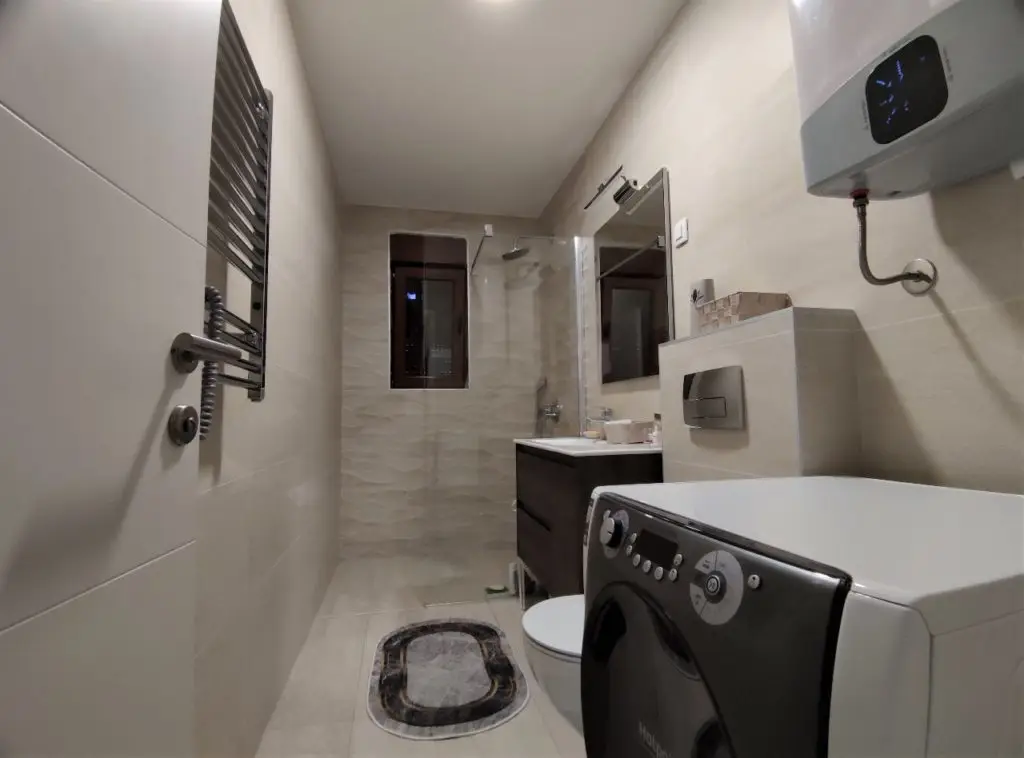 Compact bathroom with shower, sink, toilet, and washing machine