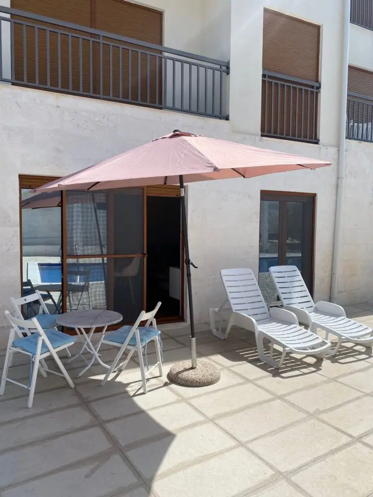 Patio with pink umbrella, table, chairs, and lounge chairs