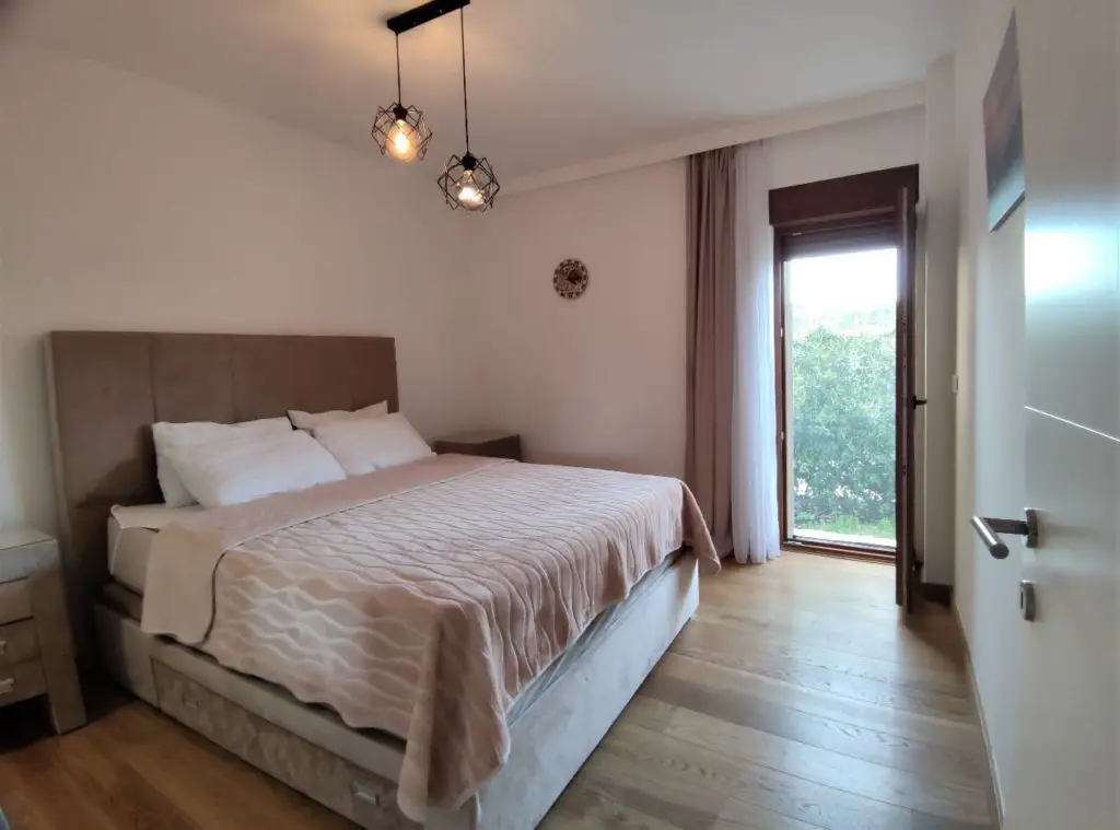 Bedroom with double bed, hanging lights, and balcony door