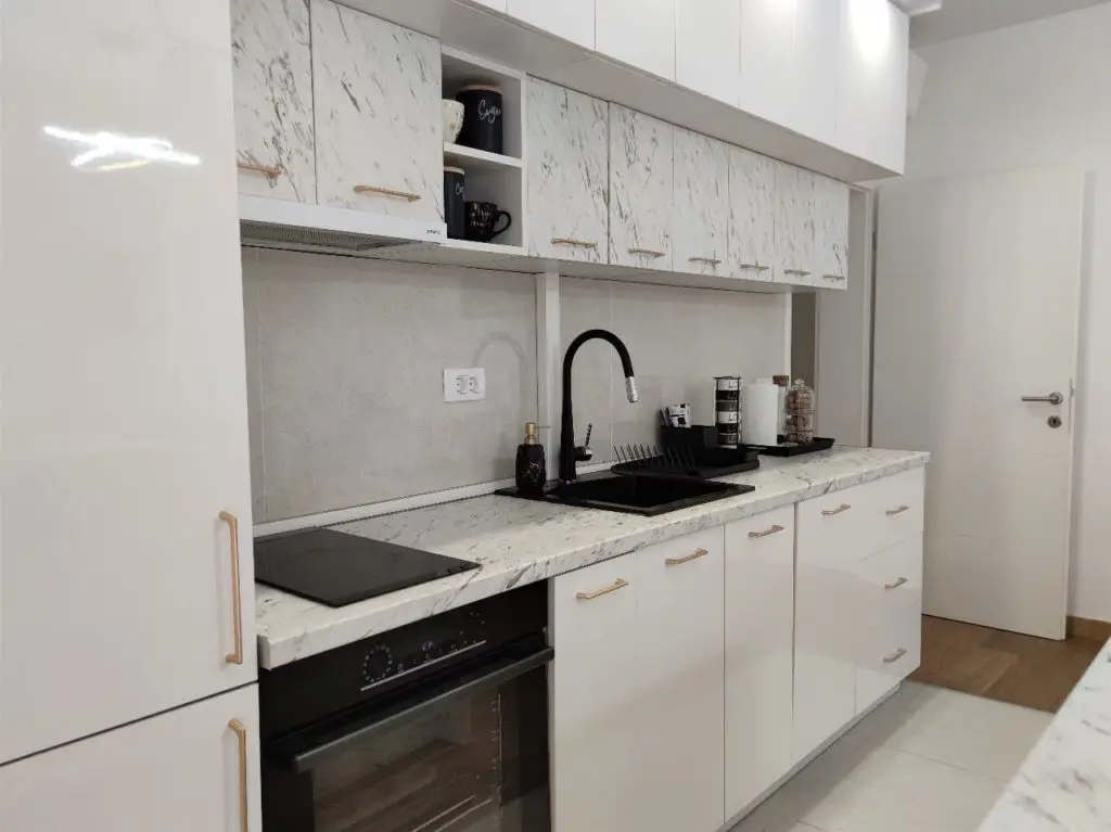 Modern white kitchen with marble countertop and black sink
