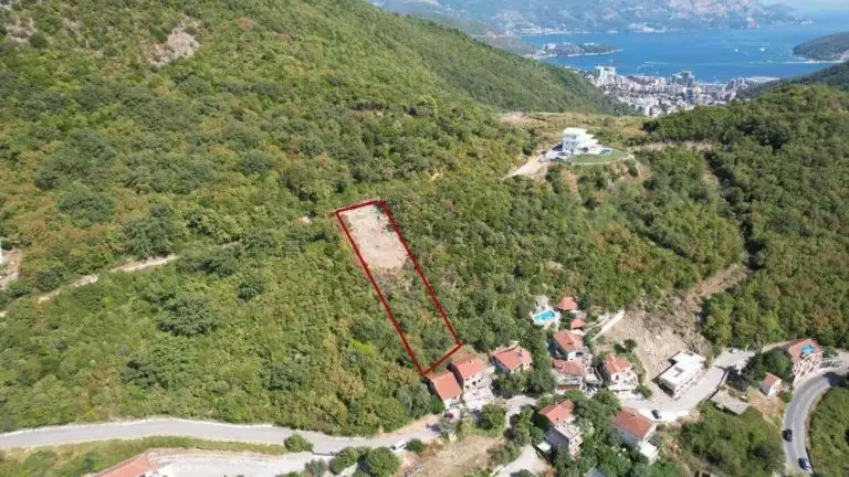 Aerial view of a red-outlined hillside plot near houses