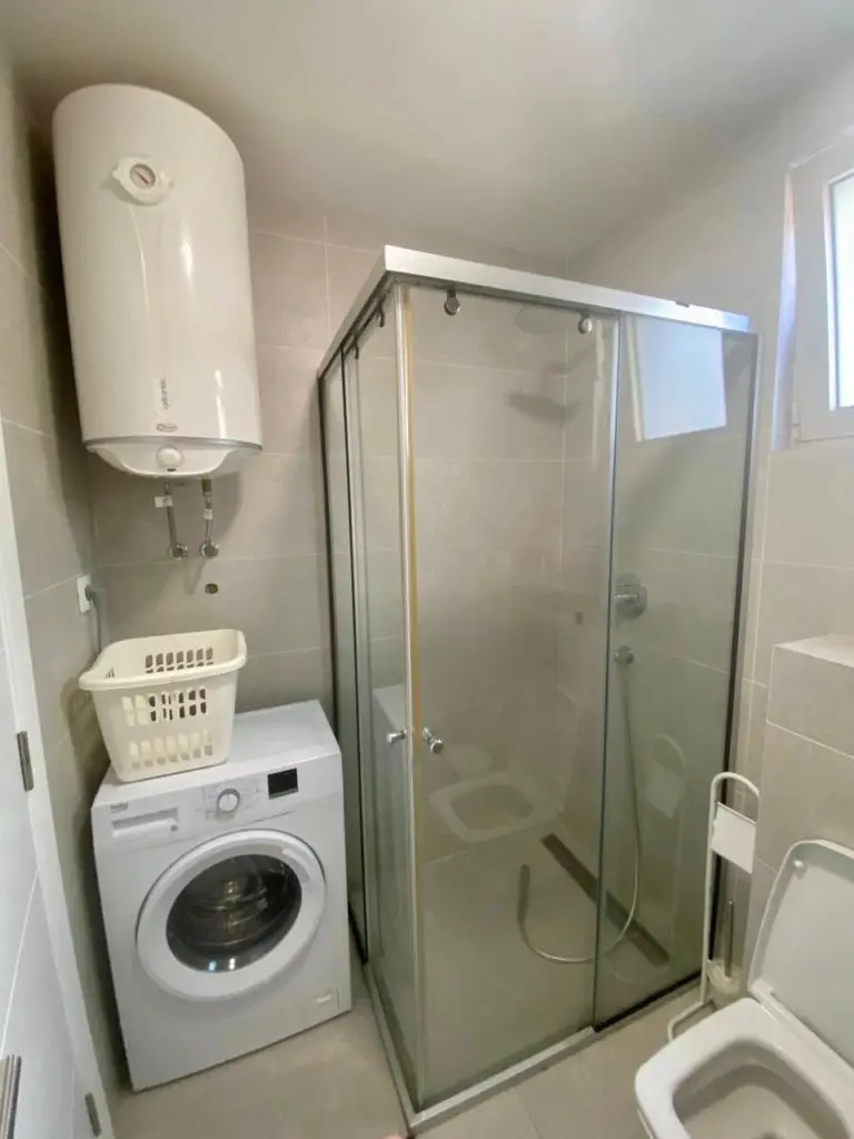 Compact bathroom with shower, washing machine, and water heater