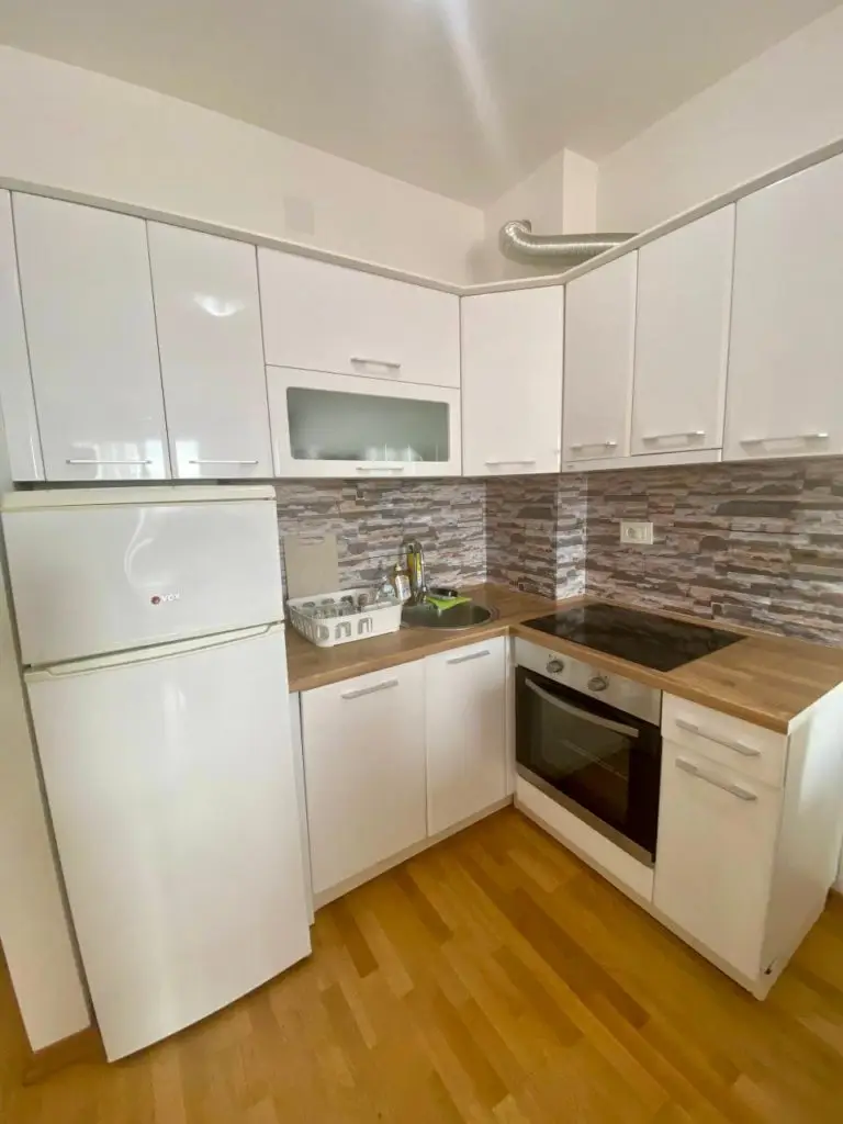 Compact white kitchen with refrigerator, stove, and sink