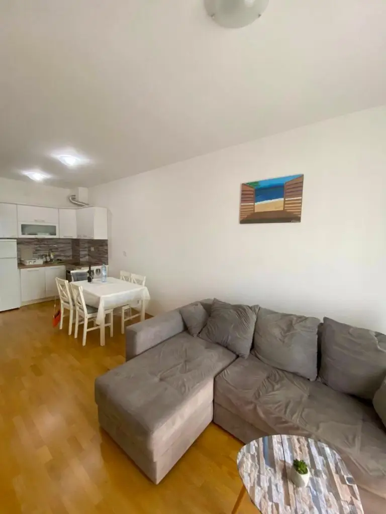 Open-plan living room with gray sectional, dining table, and kitchen