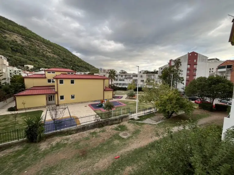 Residential courtyard with yellow building, playground, and cloudy sky