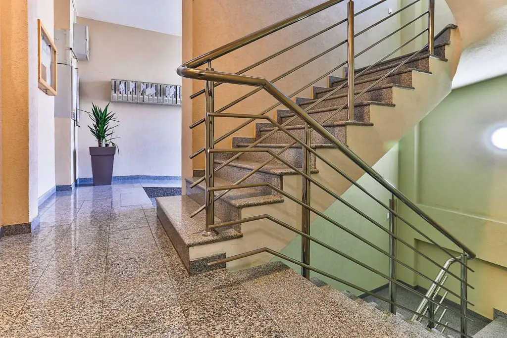 Interior stairwell with stone steps, metal railing, and potted plant