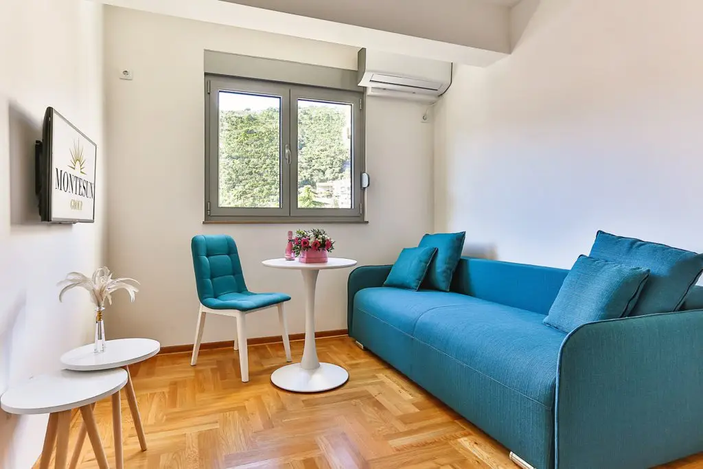 Bright studio room with blue sofa, chair, and tables