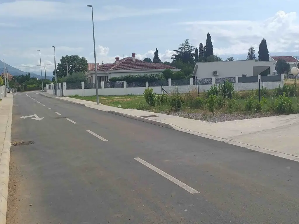 Paved residential street beside empty lots and houses