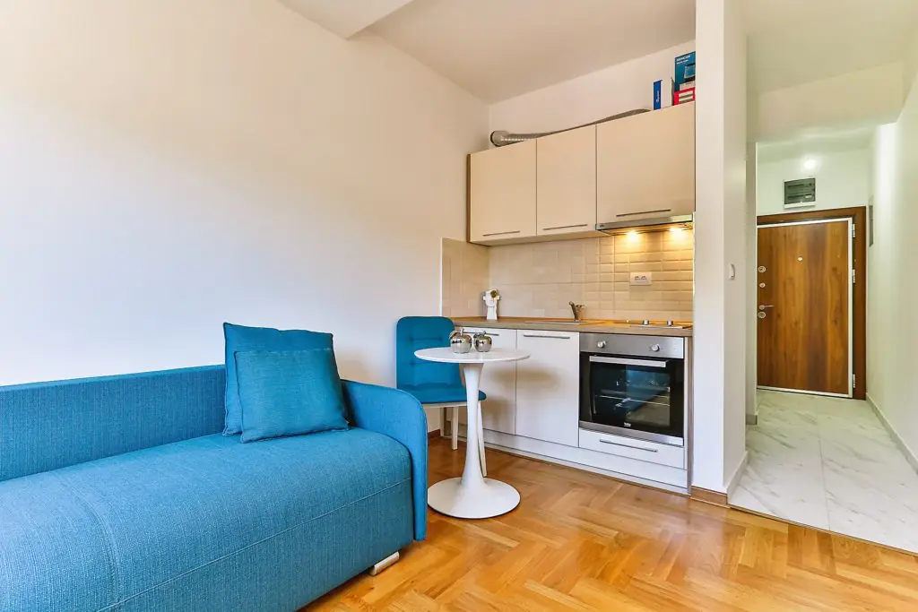 Blue sofa beside compact kitchen and round table