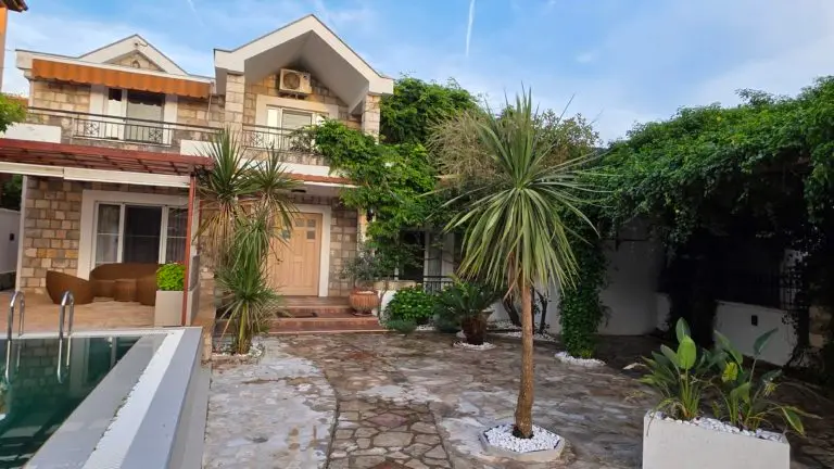 Stone house with patio, pool, and palm trees