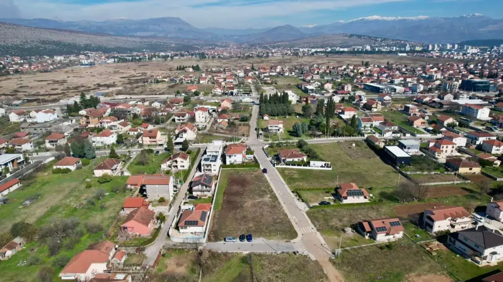Aerial view of suburban neighborhood with vacant plots and mountains