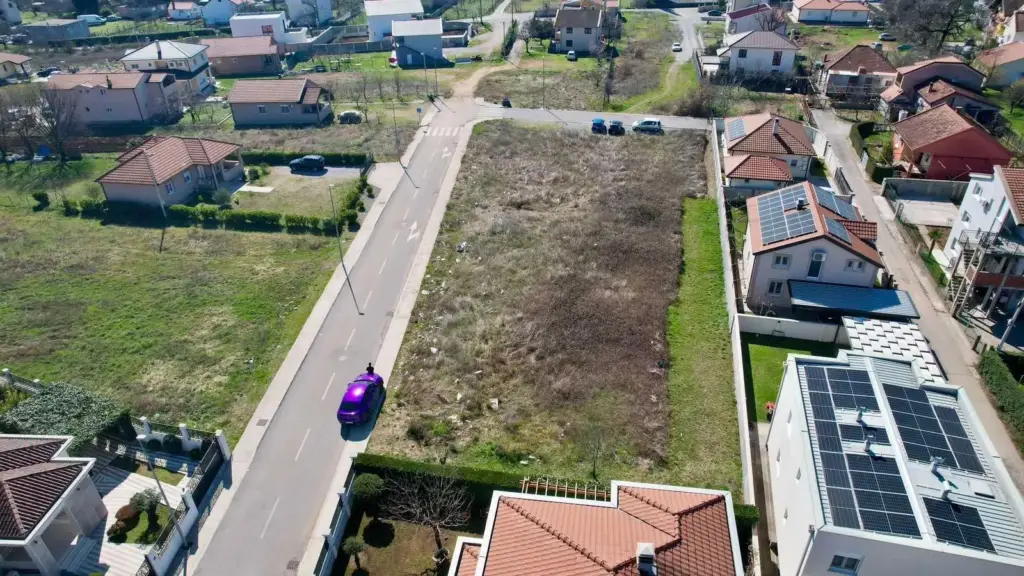 Aerial view of vacant lot beside residential street and houses